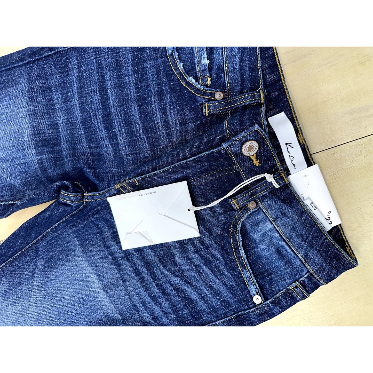 Close-up of blue jeans with a brand tag on a light wooden surface
