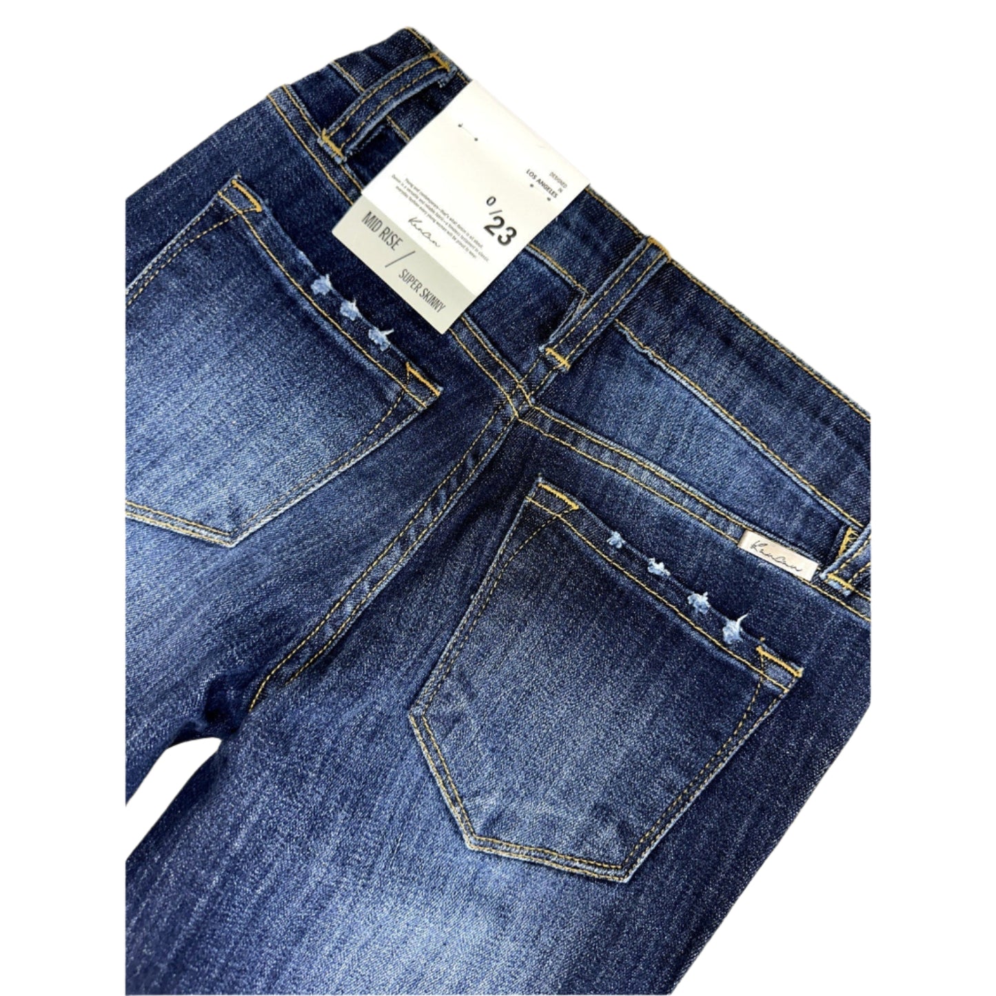 Close-up of blue jeans with a visible tag on a white surface