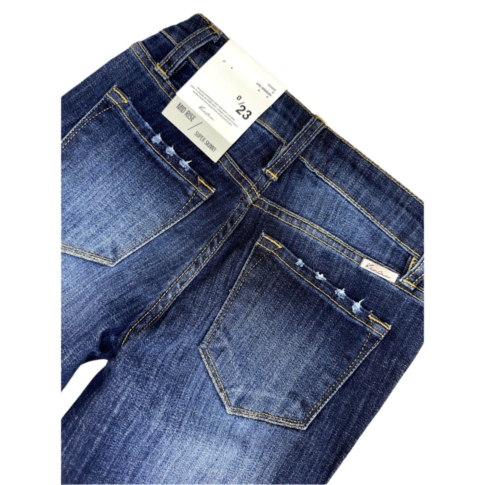 Close-up of blue jeans with a visible tag on a white surface