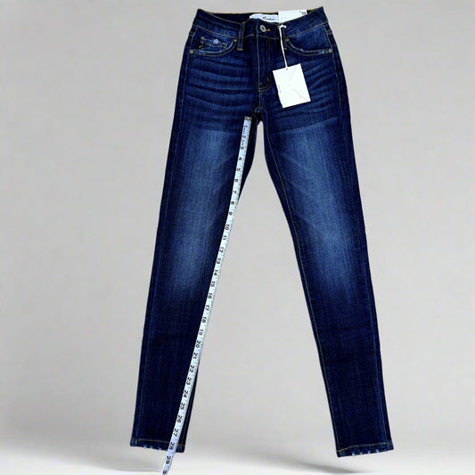 Pair of blue jeans with a measuring tape on a beige background