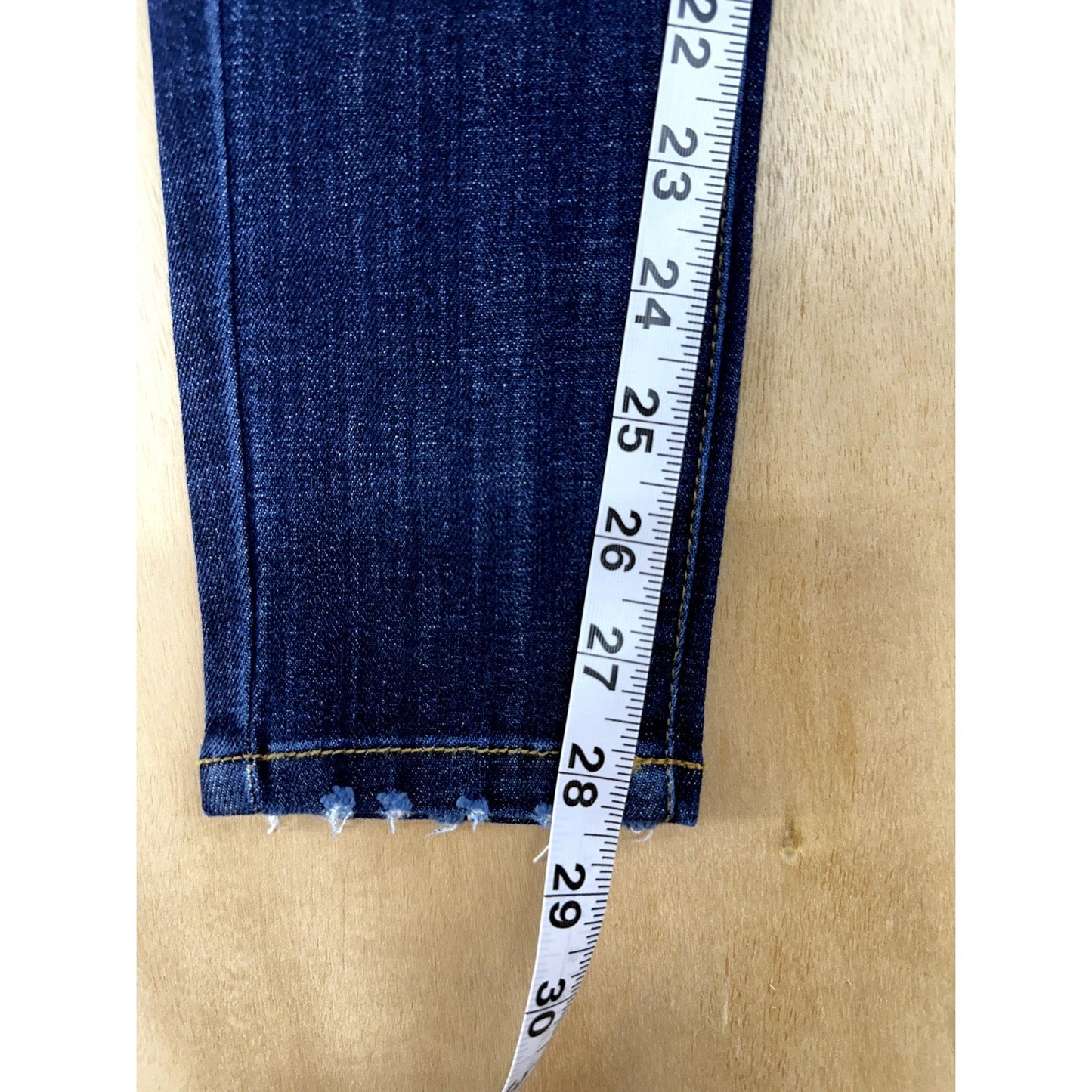 Blue jeans with a measuring tape on a wooden surface